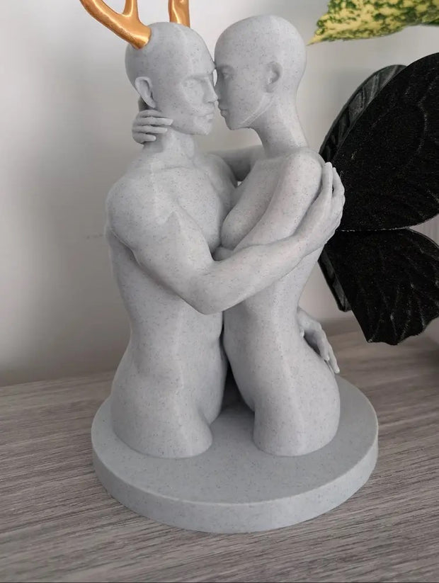 Statue of two people embracing with a butterfly on a wooden surface
