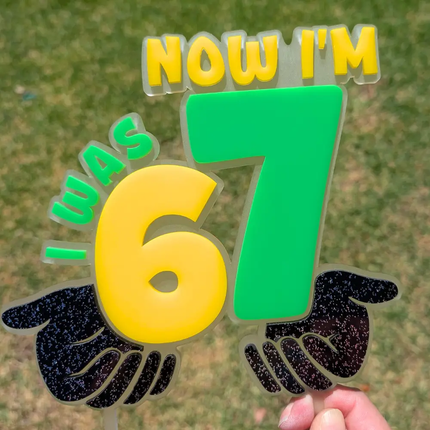 Cake toper in yellow and green that says I was 6 now I'm 7 with the 6 and 7 being large