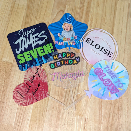 A Range of acrylic cake toppers with personalised designs on them