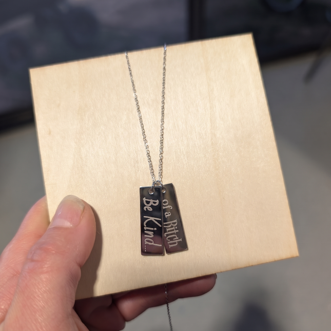 Necklace with engraved pendant held over a wooden box