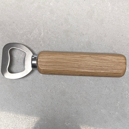A bottle opener with a silver metal blade and a light brown wooden handle, placed on a gray textured surface.