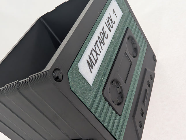 Close-up of a cassette tape with 'MIXTAP VOL 1' label on a light gray background