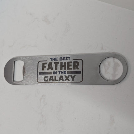 Metal bottle opener with 'The Best Father in the Galaxy' text on a white background