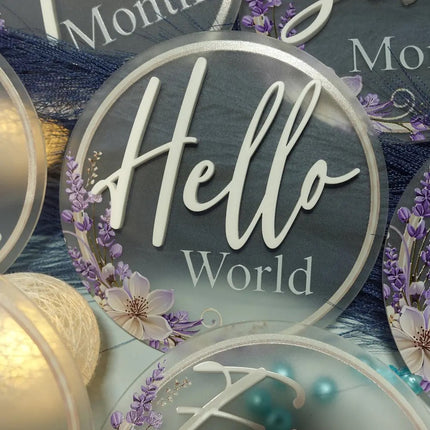 Close up of baby milestone cards with text and floral designs on a blue background. made from frosted acrylic