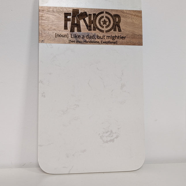 A white rectangular board with rounded corners and a natural wood label at the top reading 'FAKHOR' with smaller text below, photographed against a plain white background.
