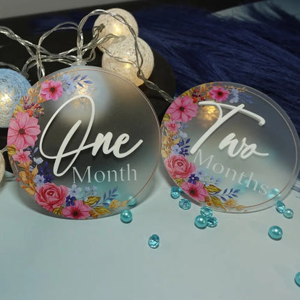 Two decorative plates with floral designs and text, surrounded by string lights and beads on a blue fabric background.