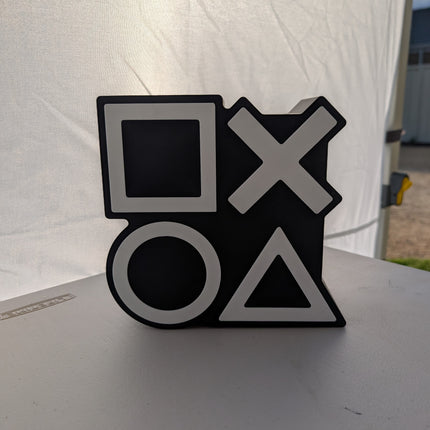 Black and white gaming controller symbol on a white surface with a white curtain background