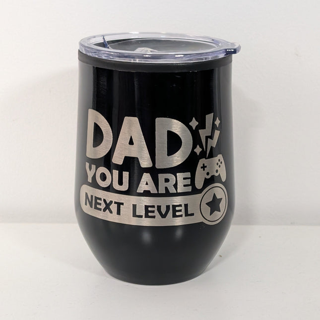 Black tumbler with 'Dad you are next level' text and gaming controller graphic on a white background