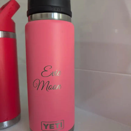 Pink YETI water bottle with 'Evie Moon'  engraved text on a white surface
