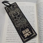 Decorative bookmark with skull design and 'Read Spicy' text on an open book.