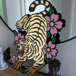 Decorative wall art with a tiger and flowers on a white wall.