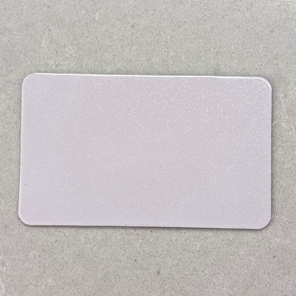 A blank, white rectangular card with rounded corners, placed on a textured gray surface.
