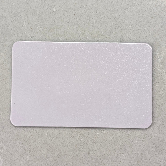 A blank, white rectangular card with rounded corners, placed on a textured gray surface.