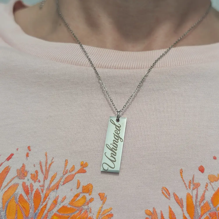 Unhinged necklace close up, the necklace in engraved with the word 'unhinged'