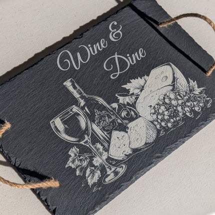 Slate cutting board with 'Wine & Dine' design on a light surface