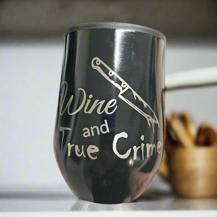 A black 350ml stainless steel travel cup with white text and design, featuring a sword and the phrase 'WINE AND TRUE CRIME'.