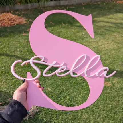 Pink decorative letter 'S' with the name 'Stella' held in a hand outdoors. made from baby pink 3mm acrylic